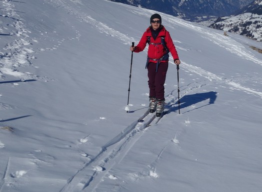 Eine Frau in roter Jacke und Sonnenbrille bei der Ankunft auf dem Gipfel vom Gritlisbord
