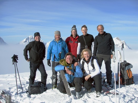 Eine Gruppe von sieben Leute posiert mit lachenden Gesichtern auf dem Gipfel des Brueschbuechels