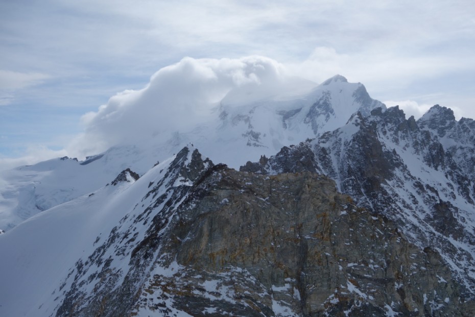 Eine weisse Wolke umhuellt einen Berggipfel in den Berner Alpen.