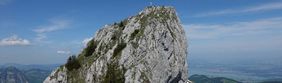 Der felsige Gipfelstock des Chopfenbergs mit Gipfelkreuz.